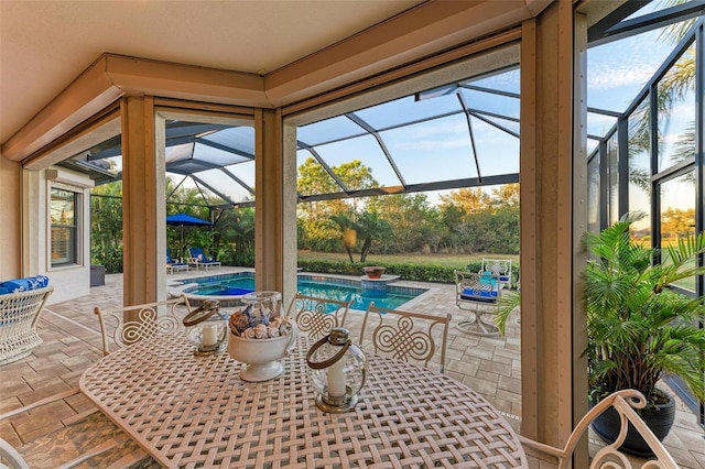 view of patio / terrace featuring glass enclosure and a pool with hot tub