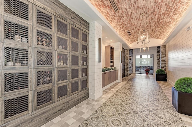 hallway featuring brick ceiling, a chandelier, and lofted ceiling