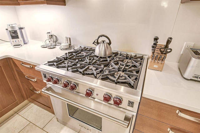 915 Seaside Drive 312, Weeks 16-17, Sarasota, FL 34242 - kitchen with designer stove, brown cabinetry, light tile patterned floors, and light countertops