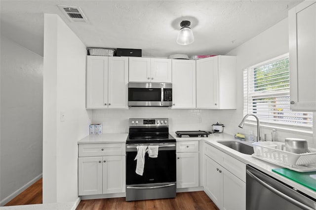 kitchen with dark hardwood / wood-style flooring, sink, stainless steel appliances, and white cabinetry