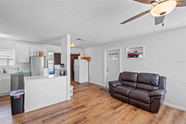 living room featuring ceiling fan, light wood-type flooring, and plenty of natural light