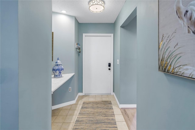 doorway to outside with light tile patterned floors and a textured ceiling