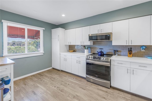 kitchen featuring decorative backsplash, stainless steel appliances, white cabinetry, and light hardwood / wood-style floors