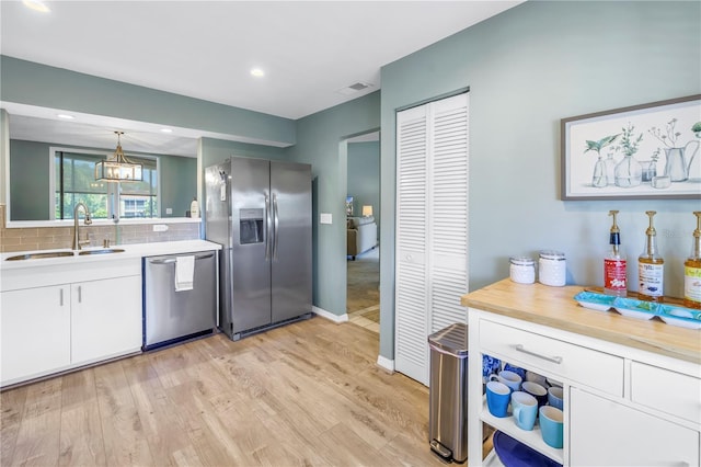 kitchen featuring backsplash, stainless steel appliances, sink, decorative light fixtures, and white cabinets