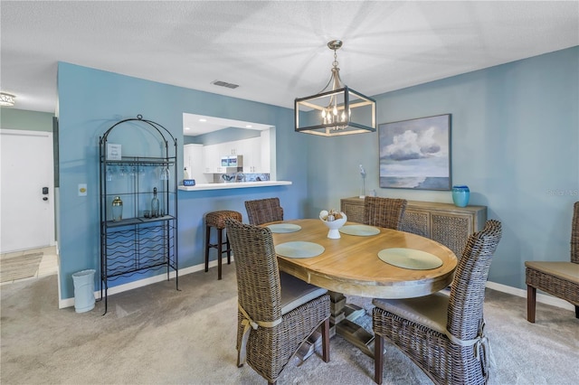 carpeted dining room featuring a textured ceiling and an inviting chandelier