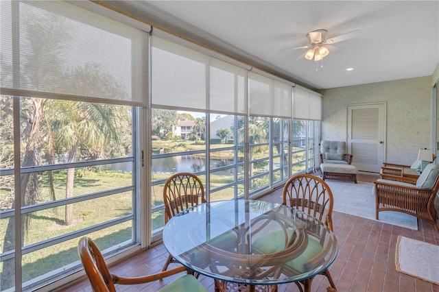 sunroom with ceiling fan, a water view, and a healthy amount of sunlight