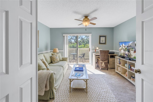 carpeted living room featuring ceiling fan and a textured ceiling