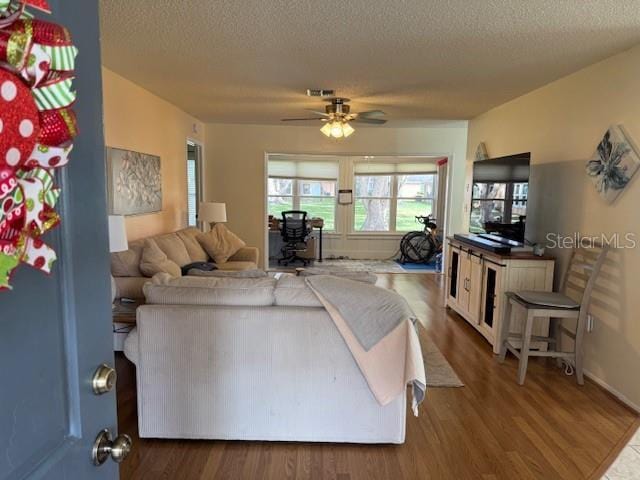 living room featuring ceiling fan, dark hardwood / wood-style flooring, and a textured ceiling