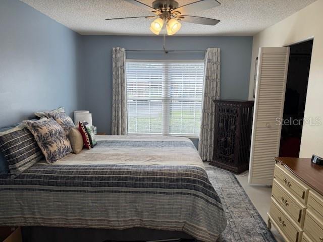 bedroom with ceiling fan and a textured ceiling