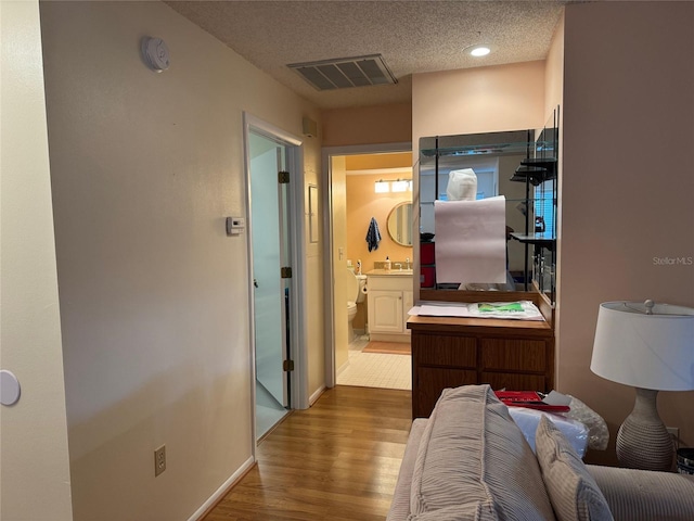 corridor with wood-type flooring, a textured ceiling, and sink