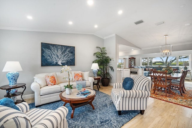 living room featuring ornamental molding, a chandelier, vaulted ceiling, and light hardwood / wood-style floors