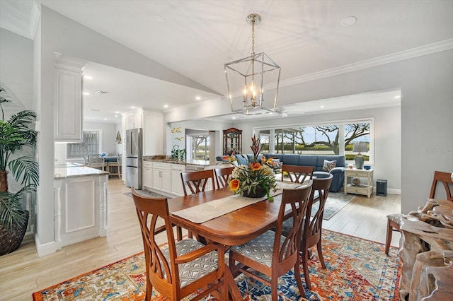 dining area featuring crown molding, light hardwood / wood-style flooring, vaulted ceiling, and sink