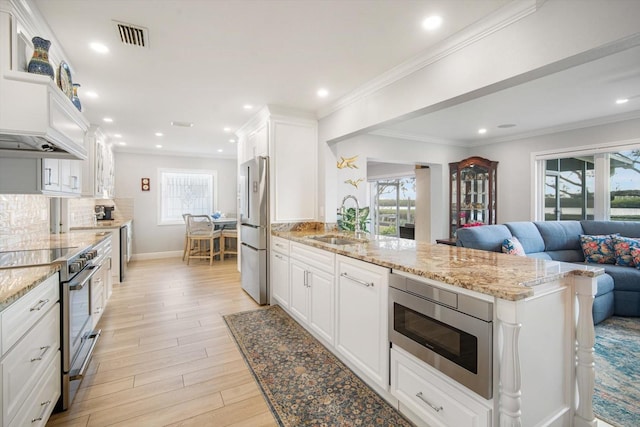 kitchen with light stone countertops, white cabinetry, sink, and stainless steel appliances