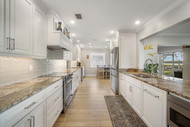 kitchen with white cabinets, light stone counters, sink, and stainless steel appliances