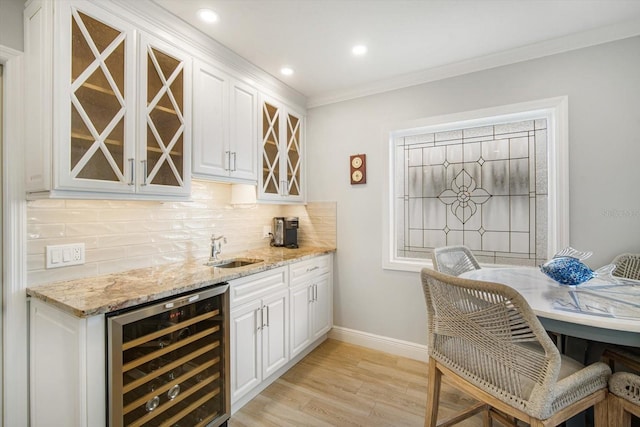 bar with white cabinets, sink, wine cooler, light hardwood / wood-style floors, and light stone counters