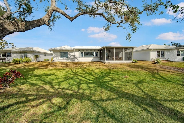 rear view of house featuring a yard and a sunroom