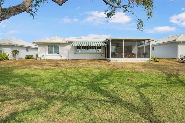 rear view of house with a lawn and a sunroom