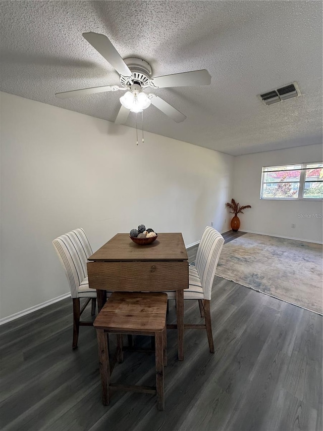 dining space with a textured ceiling, ceiling fan, and dark wood-type flooring