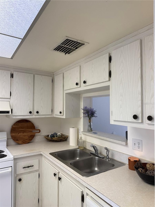 kitchen with white stove, a skylight, range hood, and sink