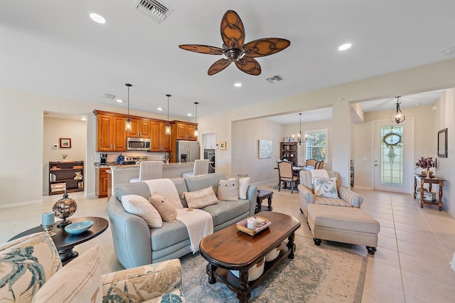 tiled living room with ceiling fan with notable chandelier