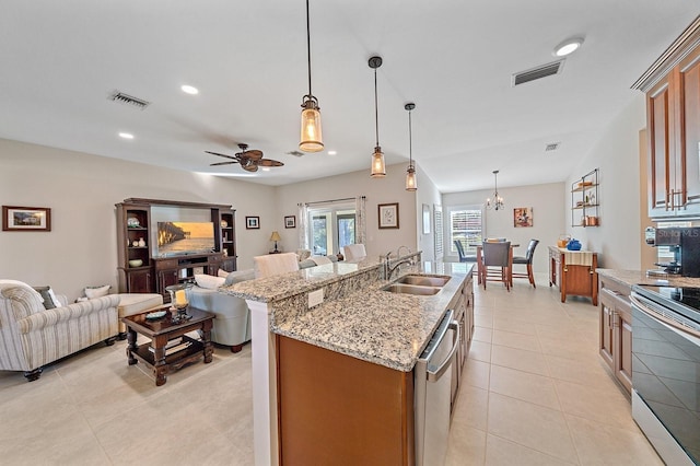 kitchen featuring pendant lighting, sink, stainless steel appliances, and an island with sink