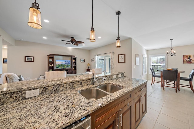 kitchen with light stone countertops, pendant lighting, ceiling fan with notable chandelier, and sink