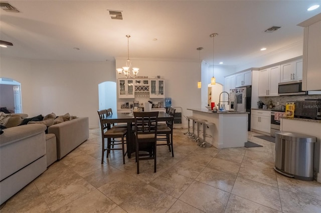 dining space with crown molding, sink, and a chandelier