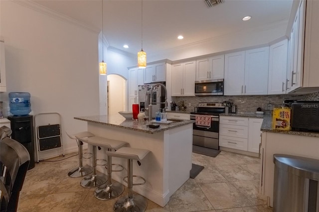 kitchen featuring light stone countertops, stainless steel appliances, pendant lighting, a center island with sink, and white cabinets