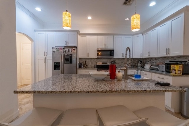 kitchen with white cabinets, decorative light fixtures, decorative backsplash, and appliances with stainless steel finishes