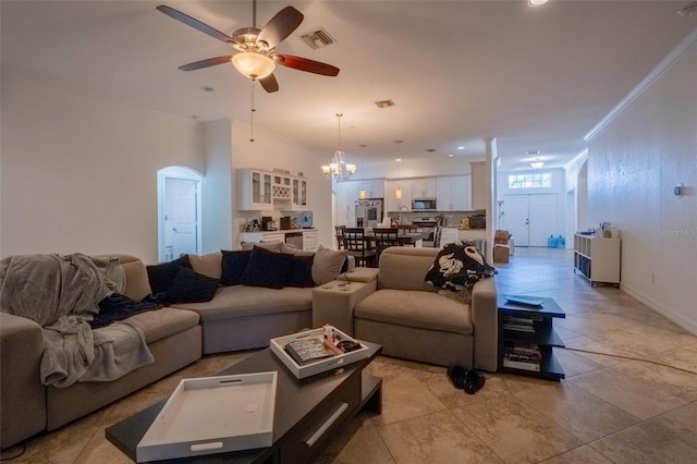 tiled living room with ceiling fan with notable chandelier and crown molding