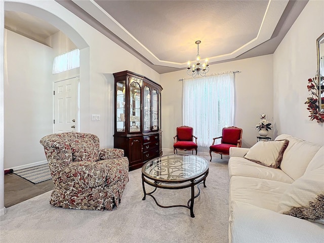 living room with a chandelier, light colored carpet, and a tray ceiling