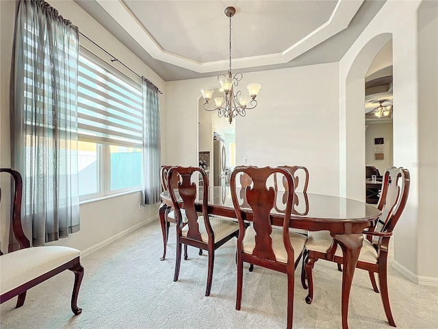 dining room with a chandelier, light carpet, and a tray ceiling