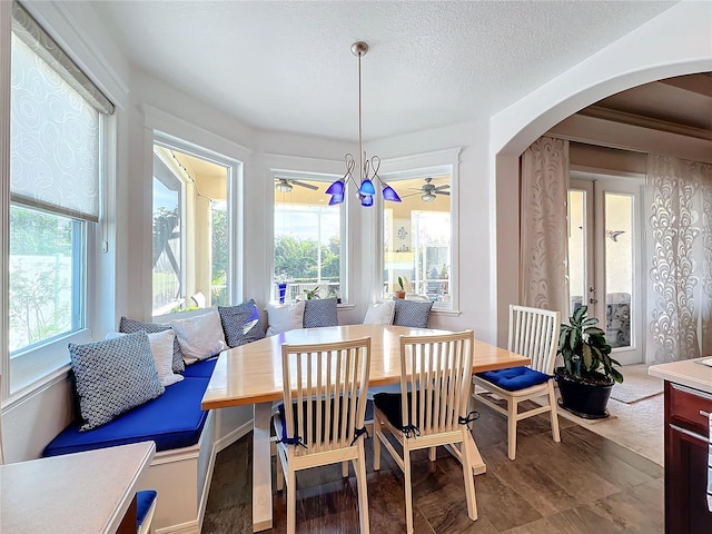 dining space with a healthy amount of sunlight, a textured ceiling, and a notable chandelier