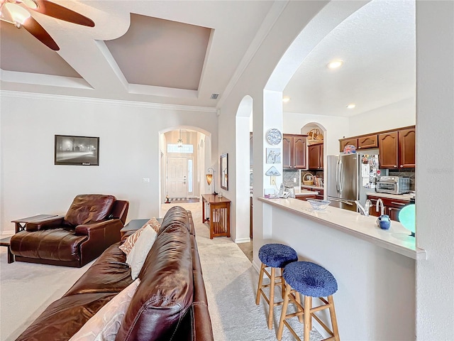 living room with light carpet, a tray ceiling, ceiling fan, and crown molding