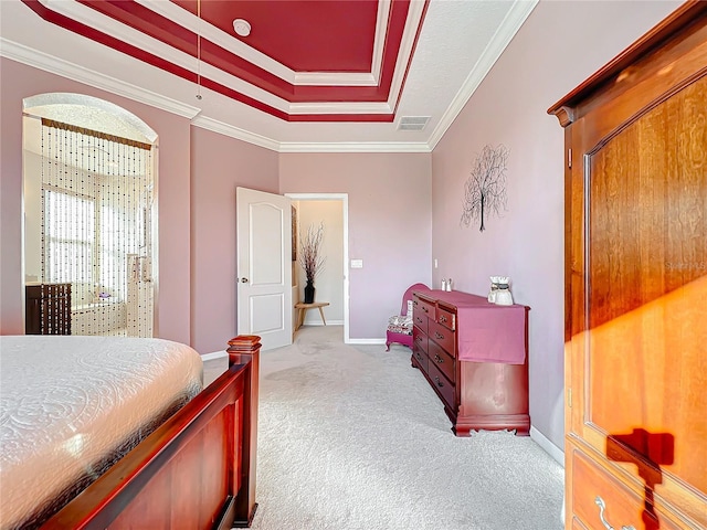 carpeted bedroom with ornamental molding and a tray ceiling