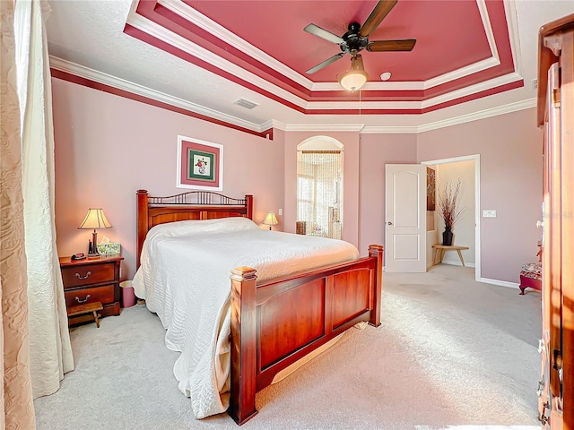 bedroom featuring a tray ceiling, ceiling fan, ornamental molding, and light colored carpet