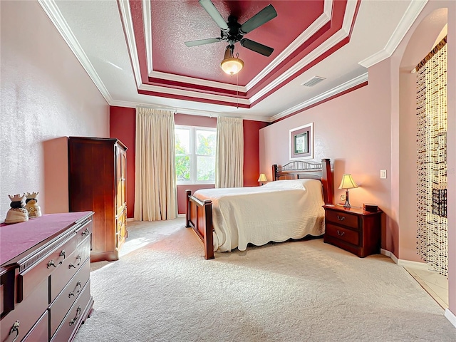 bedroom featuring a tray ceiling, ceiling fan, light carpet, and ornamental molding