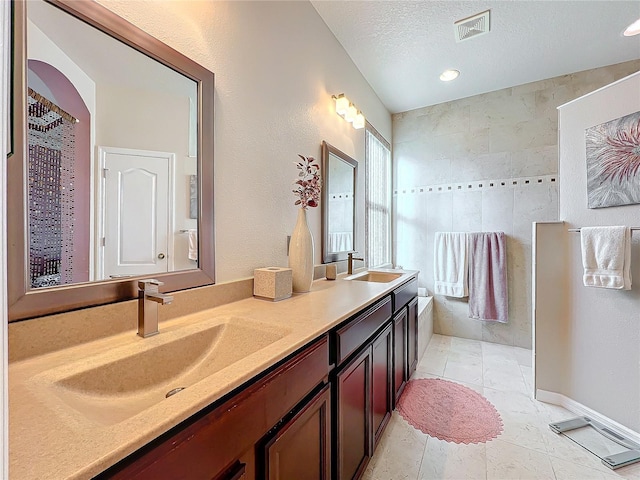 bathroom with tile patterned floors, vanity, and a textured ceiling