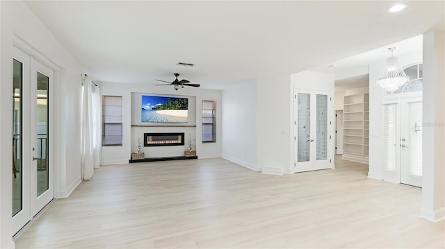 unfurnished living room with french doors, a glass covered fireplace, visible vents, and light wood-style floors