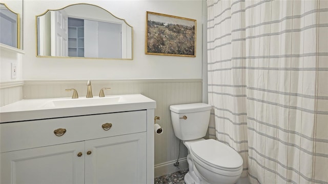 bathroom with wainscoting, vanity, and toilet