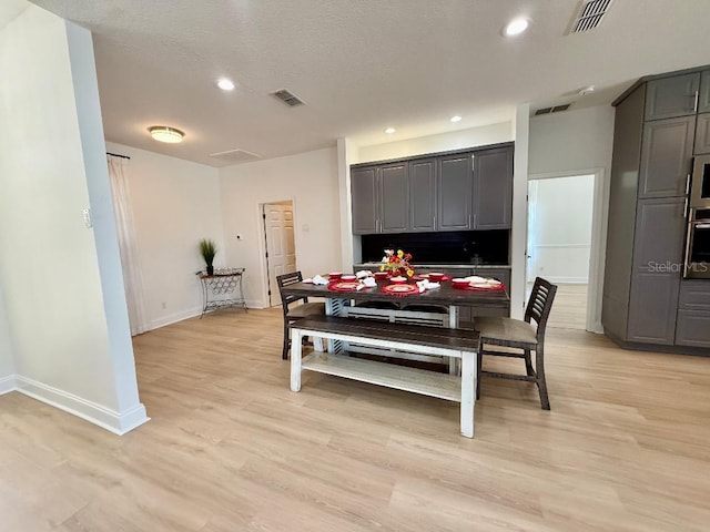 dining space with light wood-style flooring, visible vents, and baseboards