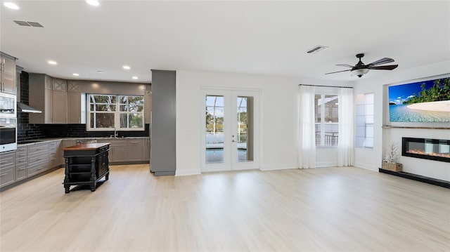 living area featuring light wood-style floors, visible vents, and a glass covered fireplace