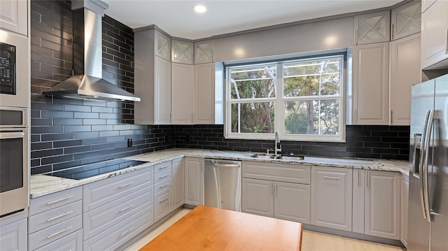 kitchen featuring decorative backsplash, appliances with stainless steel finishes, glass insert cabinets, a sink, and wall chimney exhaust hood