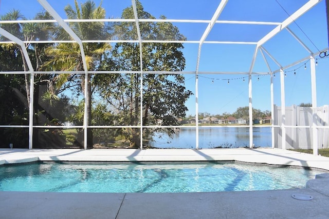 pool featuring glass enclosure, a patio, and a water view