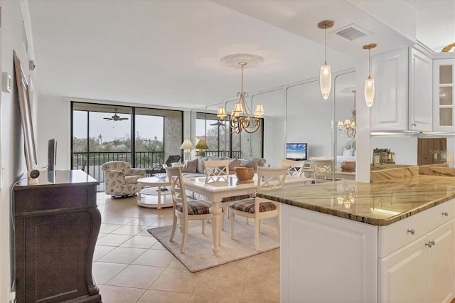 kitchen featuring white cabinets, a wall of windows, dark stone counters, and hanging light fixtures