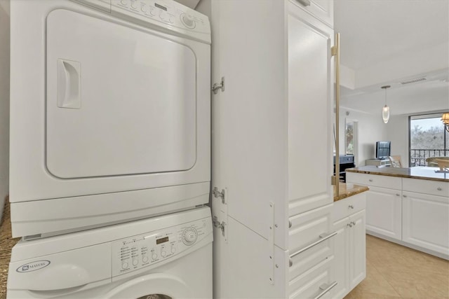 laundry room featuring light tile patterned floors and stacked washer / dryer