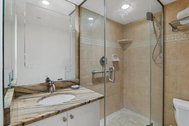 bathroom with vanity, a shower with shower door, and toilet