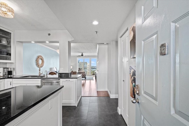 kitchen with dishwasher, dark stone counters, ceiling fan, a textured ceiling, and white cabinetry