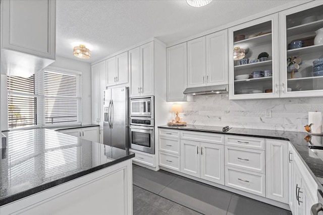 kitchen with backsplash, dark stone counters, white cabinets, dark tile patterned floors, and stainless steel appliances