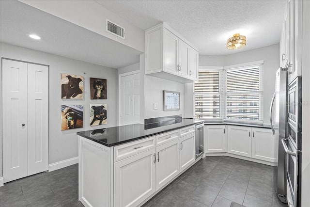 kitchen with kitchen peninsula, oven, dark tile patterned flooring, white cabinetry, and wine cooler